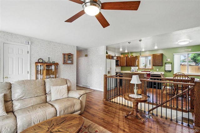 living room with ceiling fan, wallpapered walls, and wood finished floors