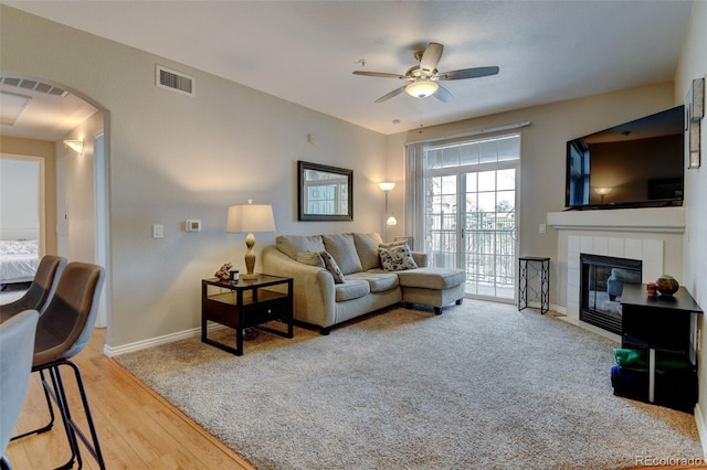 living room featuring baseboards, visible vents, a fireplace, and light wood finished floors