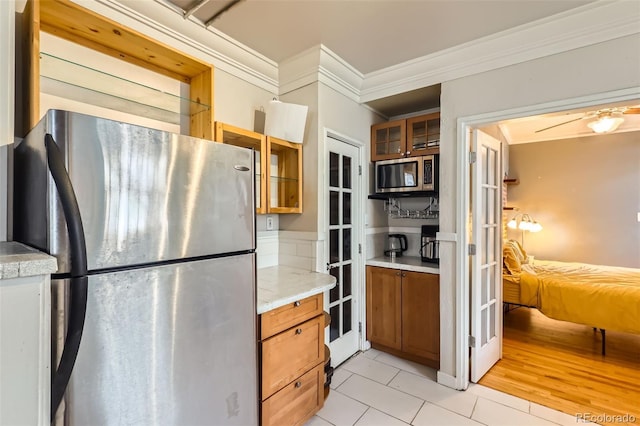1376 N Pearl St Unit B1, Denver, CO 80203 - kitchen featuring brown cabinetry, appliances with stainless steel finishes, crown molding, and light tile patterned floors