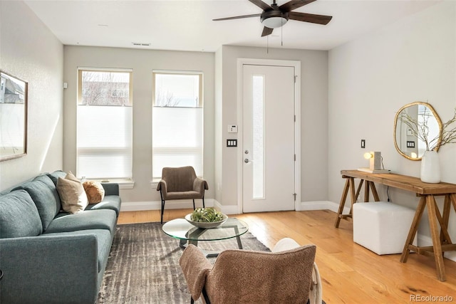 living area with light wood-type flooring, baseboards, visible vents, and a ceiling fan