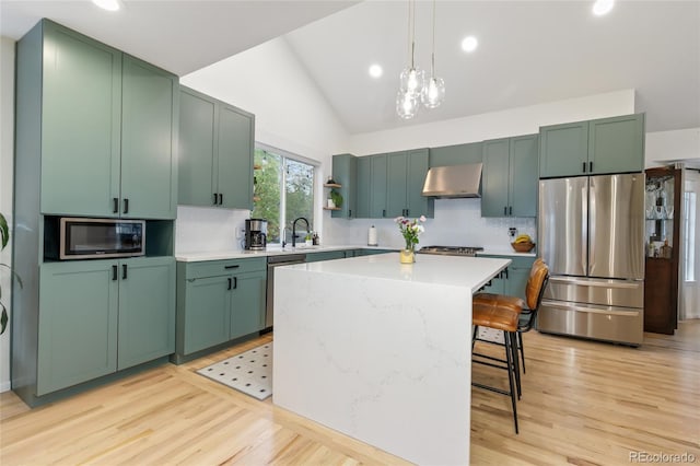 1540 Meachum Way, Erie, CO 80516 - kitchen featuring appliances with stainless steel finishes, extractor fan, lofted ceiling, tasteful backsplash, and hanging light fixtures