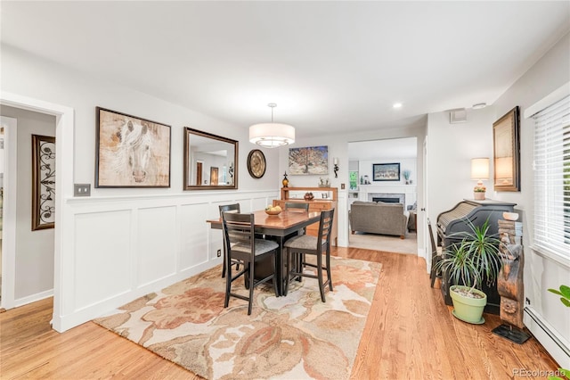 3317 Harlan St, Wheat Ridge, CO 80033 - dining space featuring a baseboard heating unit, light wood-style floors, a fireplace, recessed lighting, and wainscoting