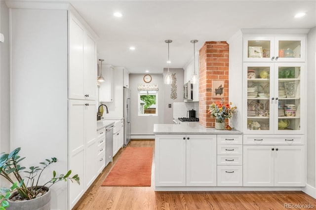 3317 Harlan St, Wheat Ridge, CO 80033 - kitchen featuring appliances with stainless steel finishes, white cabinets, a baseboard radiator, light wood finished floors, and a peninsula