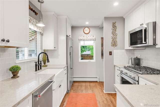 3317 Harlan St, Wheat Ridge, CO 80033 - kitchen with stainless steel appliances, a baseboard heating unit, light wood-style flooring, healthy amount of natural light, and recessed lighting