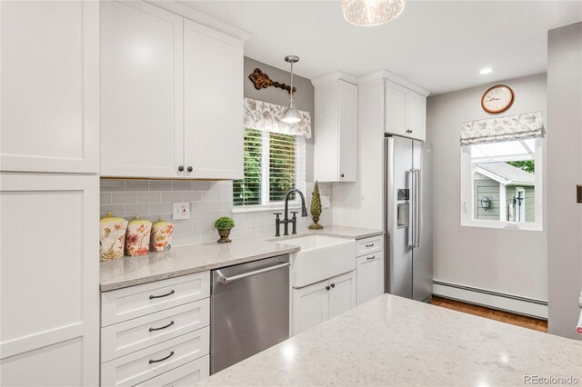3317 Harlan St, Wheat Ridge, CO 80033 - kitchen featuring stainless steel appliances, a baseboard heating unit, a sink, white cabinetry, and decorative backsplash