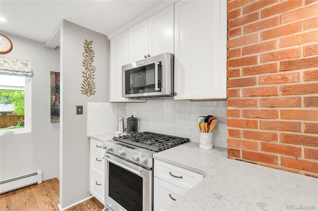 3317 Harlan St, Wheat Ridge, CO 80033 - kitchen with stainless steel appliances, baseboard heating, light wood-type flooring, backsplash, and white cabinetry
