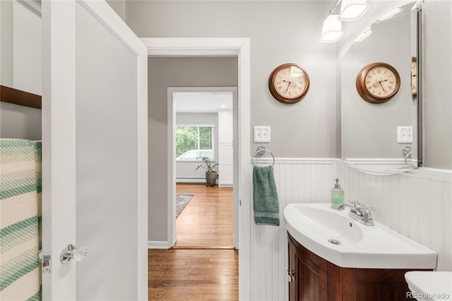 3317 Harlan St, Wheat Ridge, CO 80033 - full bathroom with wood finished floors, a wainscoted wall, vanity, toilet, and baseboard heating