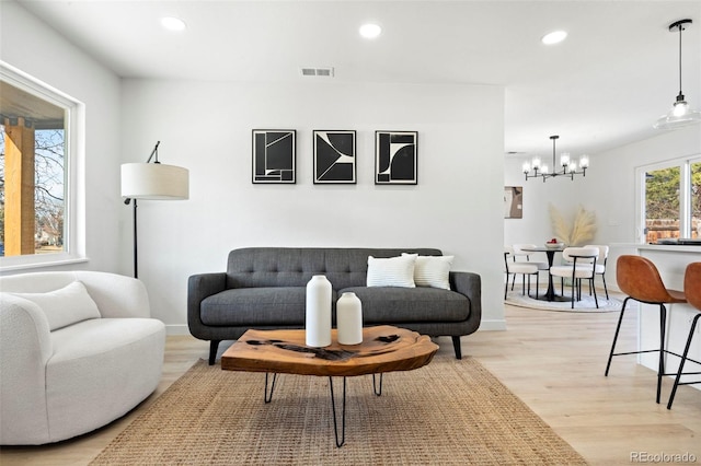 living area with light wood-type flooring, recessed lighting, visible vents, and a chandelier