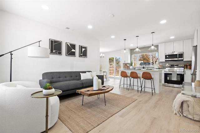 living room featuring light wood finished floors, visible vents, and recessed lighting