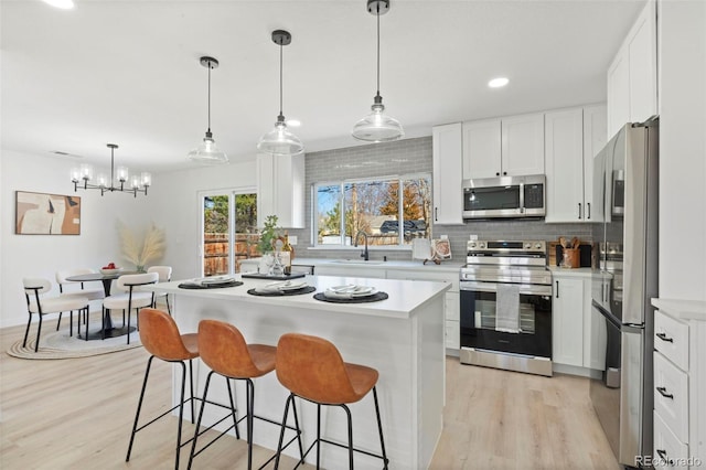 kitchen with backsplash, appliances with stainless steel finishes, light countertops, and a kitchen breakfast bar