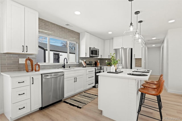 kitchen featuring stainless steel appliances, light wood-style flooring, and white cabinetry