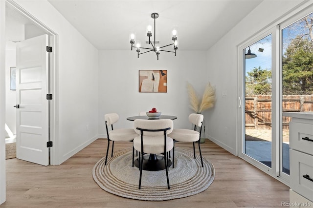 dining space featuring baseboards, a notable chandelier, and light wood-style flooring