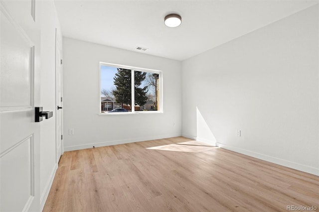 empty room featuring light wood finished floors, visible vents, and baseboards