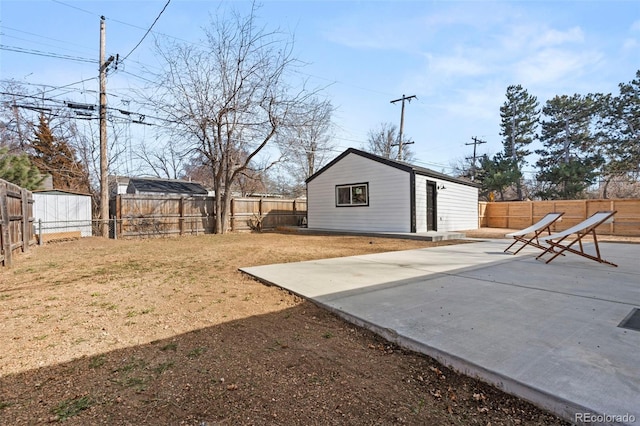 view of yard featuring an outdoor structure, a fenced backyard, and a patio