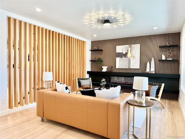 living room featuring light wood-style flooring, a glass covered fireplace, and recessed lighting