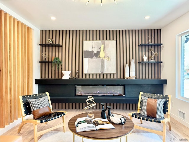 sitting room with a fireplace, wood finished floors, visible vents, and recessed lighting