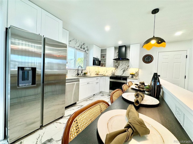 kitchen with marble finish floor, decorative light fixtures, stainless steel appliances, white cabinets, and wall chimney range hood