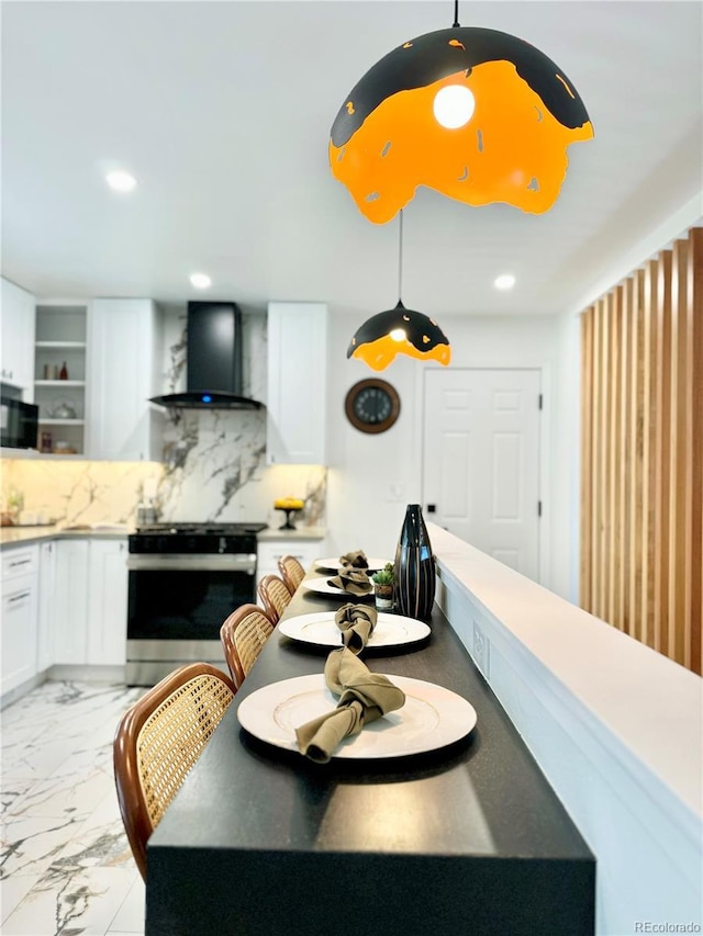 kitchen with marble finish floor, stainless steel range, tasteful backsplash, white cabinetry, and wall chimney range hood