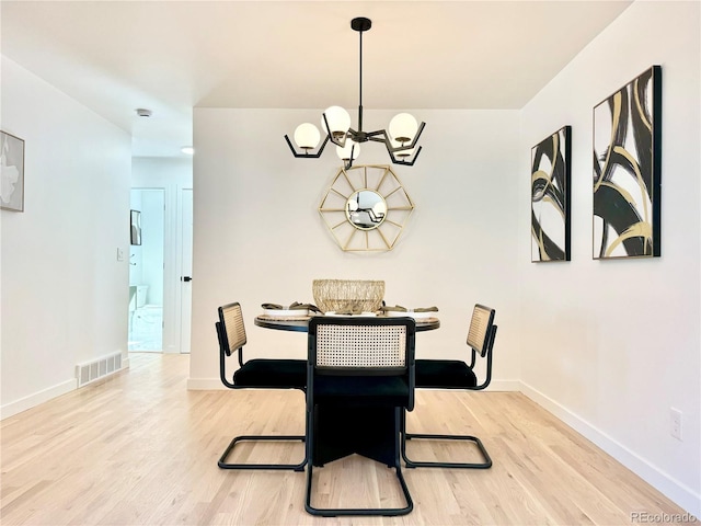 dining space featuring baseboards, light wood-style flooring, visible vents, and an inviting chandelier