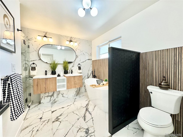 full bathroom featuring stone wall, toilet, marble finish floor, a soaking tub, and double vanity