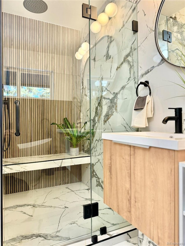 full bath featuring marble finish floor, a shower stall, stone wall, and vanity