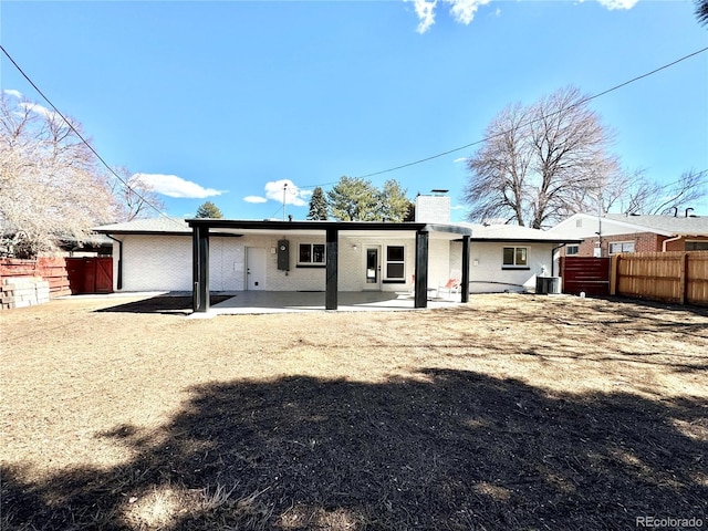 back of house featuring a fenced backyard, a patio, a chimney, and central air condition unit