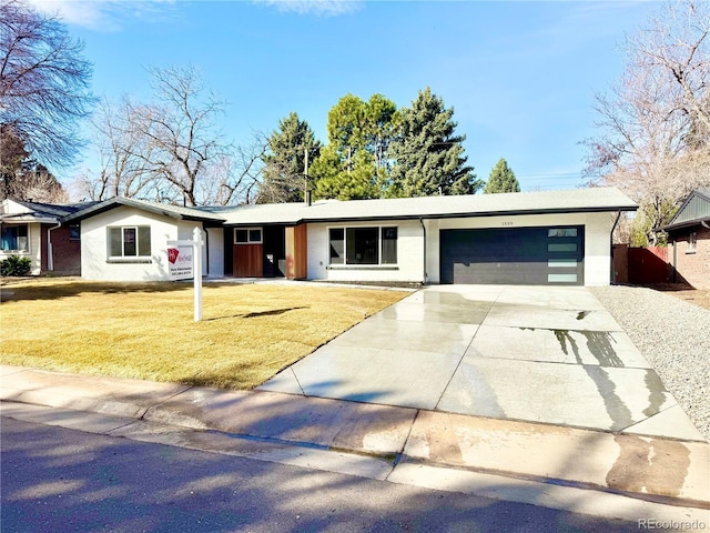 ranch-style home featuring an attached garage, stucco siding, a front yard, and concrete driveway