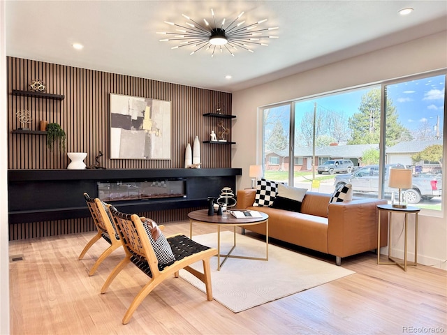 living area with a glass covered fireplace, wood finished floors, and recessed lighting