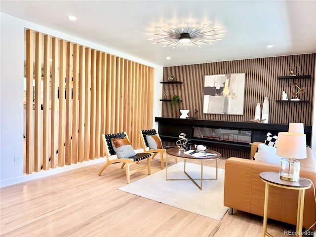 living area featuring a glass covered fireplace, wood finished floors, and recessed lighting