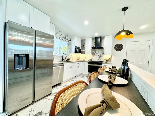 kitchen with a sink, marble finish floor, white cabinetry, wall chimney exhaust hood, and appliances with stainless steel finishes