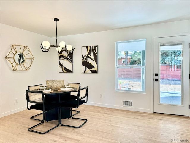 dining area with baseboards, an inviting chandelier, visible vents, and light wood-style flooring