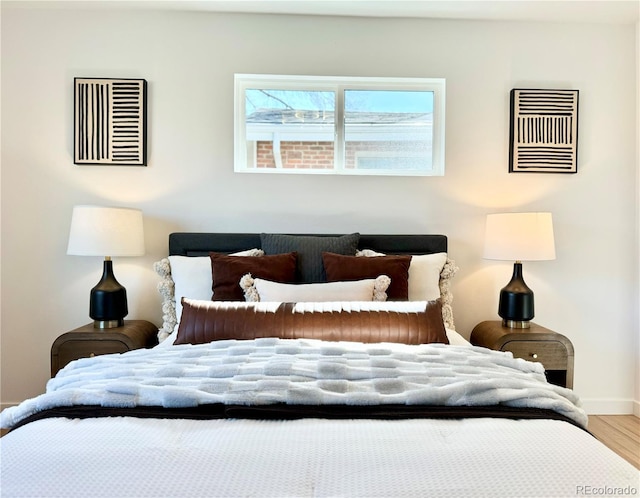 bedroom with baseboards, wood finished floors, and visible vents