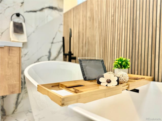 bathroom featuring marble finish floor and a freestanding tub