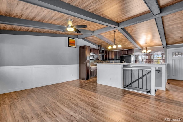 kitchen with dark brown cabinetry, light hardwood / wood-style floors, black fridge, and wall chimney range hood