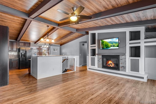 unfurnished living room with ceiling fan with notable chandelier, vaulted ceiling with beams, light hardwood / wood-style flooring, and a fireplace