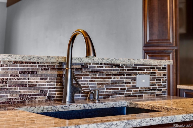 interior details featuring light stone countertops and sink