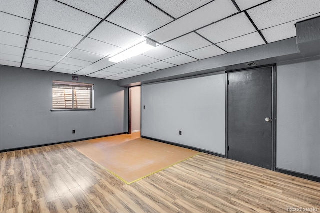 basement with a drop ceiling and light hardwood / wood-style floors