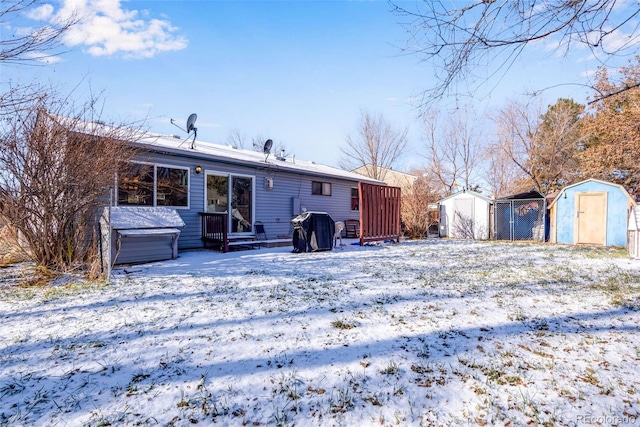 snow covered rear of property with a storage shed