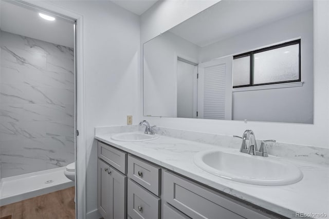 bathroom featuring vanity, tiled shower, hardwood / wood-style floors, and toilet