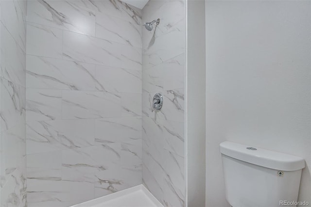 bathroom with a tile shower and toilet