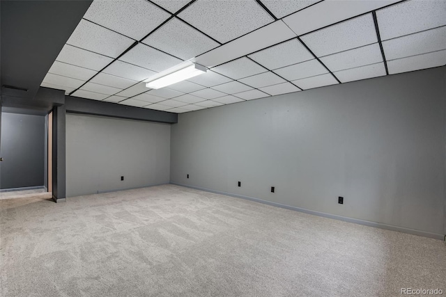 basement with a paneled ceiling and light colored carpet