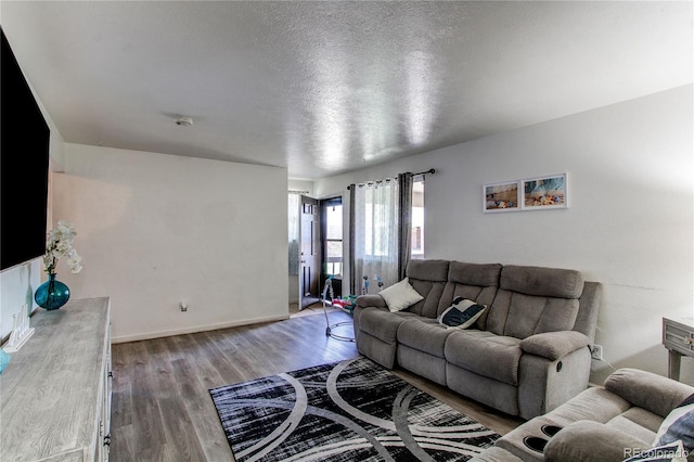 living room with baseboards, a textured ceiling, and wood finished floors