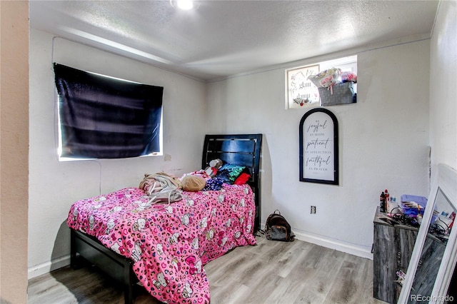 bedroom with baseboards, a textured ceiling, and wood finished floors