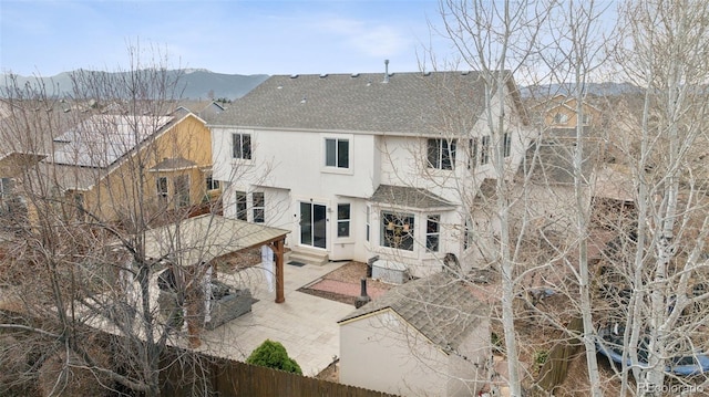 back of property with fence, a shingled roof, a patio, and stucco siding