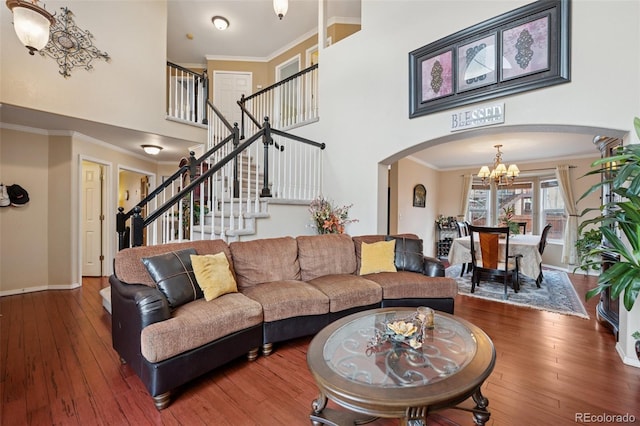 living area featuring stairs, crown molding, hardwood / wood-style flooring, arched walkways, and an inviting chandelier