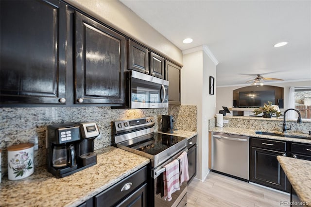 kitchen featuring decorative backsplash, ornamental molding, stainless steel appliances, a ceiling fan, and a sink