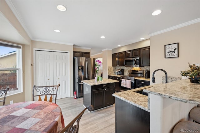 kitchen featuring tasteful backsplash, ornamental molding, a sink, light wood finished floors, and appliances with stainless steel finishes