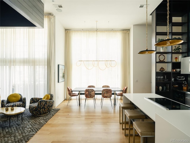 interior space with decorative light fixtures, a wealth of natural light, light wood-type flooring, and black electric cooktop