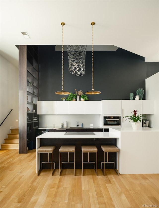 kitchen with light hardwood / wood-style floors, white cabinets, and wall oven