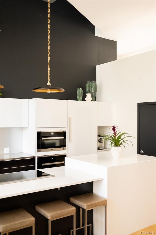 kitchen featuring black electric stovetop, a kitchen breakfast bar, and white cabinets